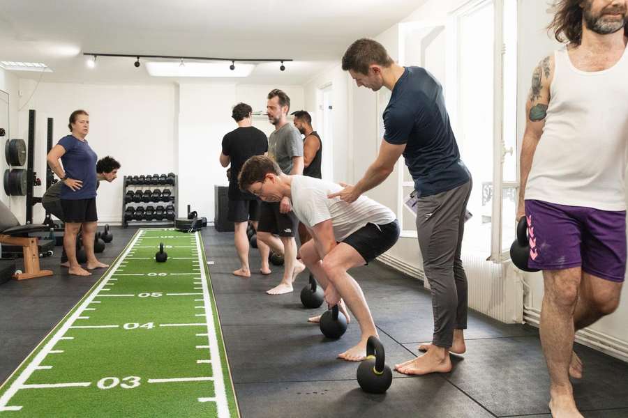 A coach corrects a kettlebell swing