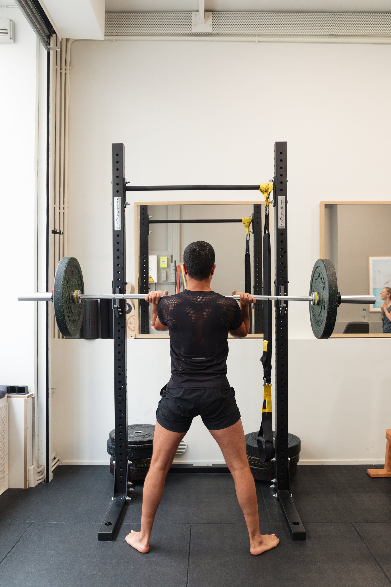 Barbell squat supervised by a coach